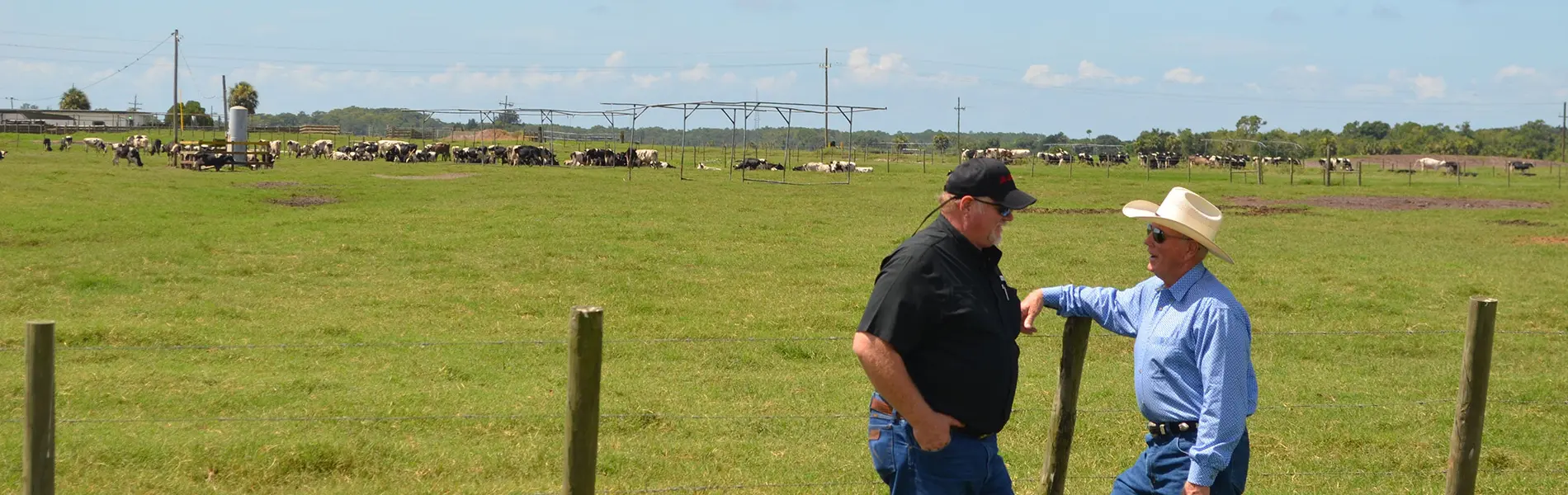 Larson Family Two men talking with Larson Farms in the background.